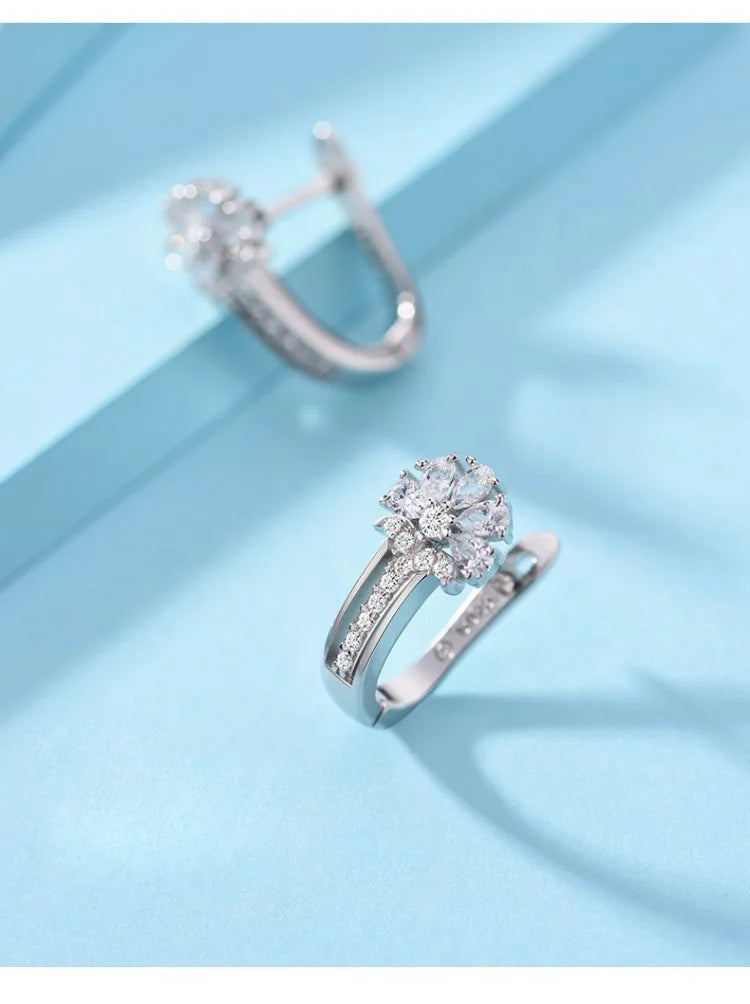 Alt Tag: 925 sterling silver zircon flower earrings hoop huggie style with sparkling flower cluster and pavé band on blue background