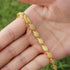 gold Islamic necklace 70cm displayed on a hand with a lush green background.