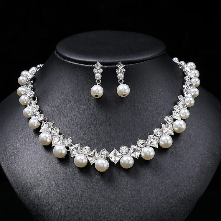 Alt Tag: pearl necklace and earrings set for women featuring white pearls and crystal rhinestones on black display bust