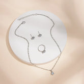 Alt Tag: 5 piece crystal jewelry set for women silver tone necklace with crystal pendant, stud earrings and ring on display