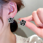 Alt Tag: crystal flower rhinestone choker necklace set black rose crystal stud earrings close-up on ear and hand
